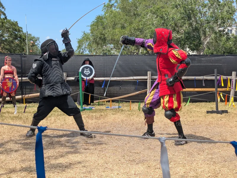 Steel Ring Academy Instructor Jason and student Galloway in saber guards mid-fight  at the St Peterburg Renaissance Faire.