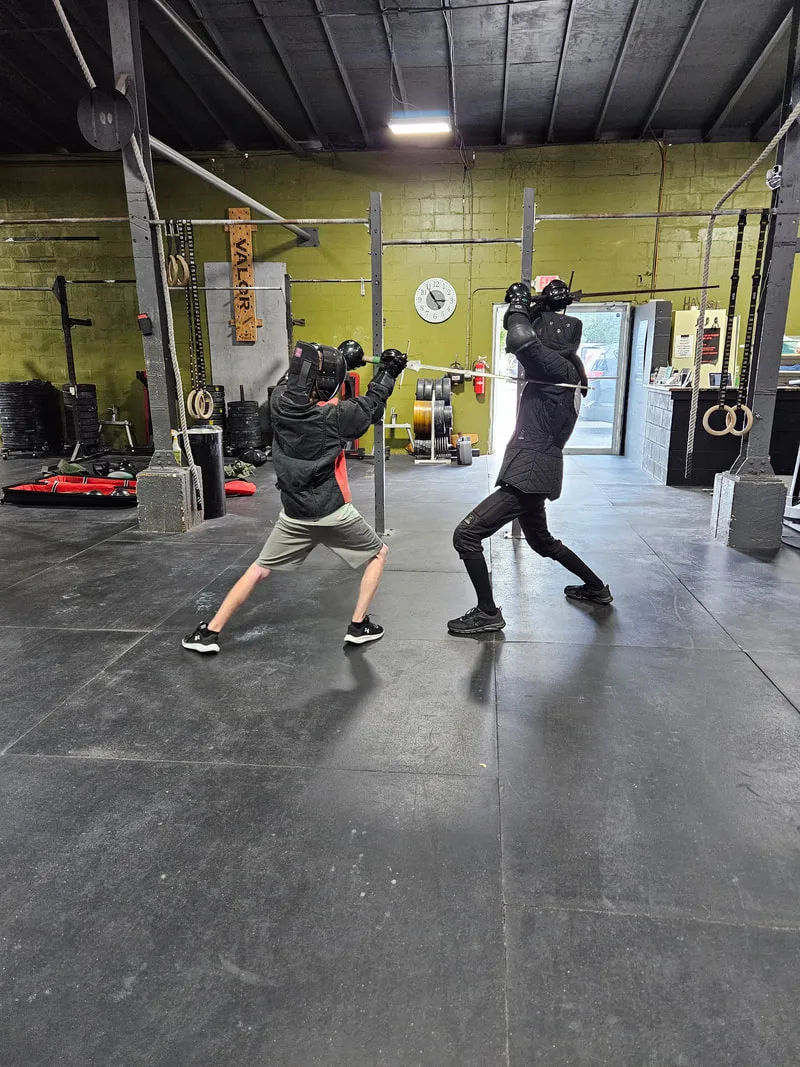 Teen student strikes Braam during a longsword fight.