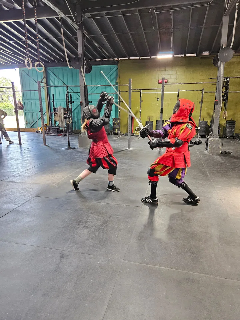 Teens sparring with longswords.