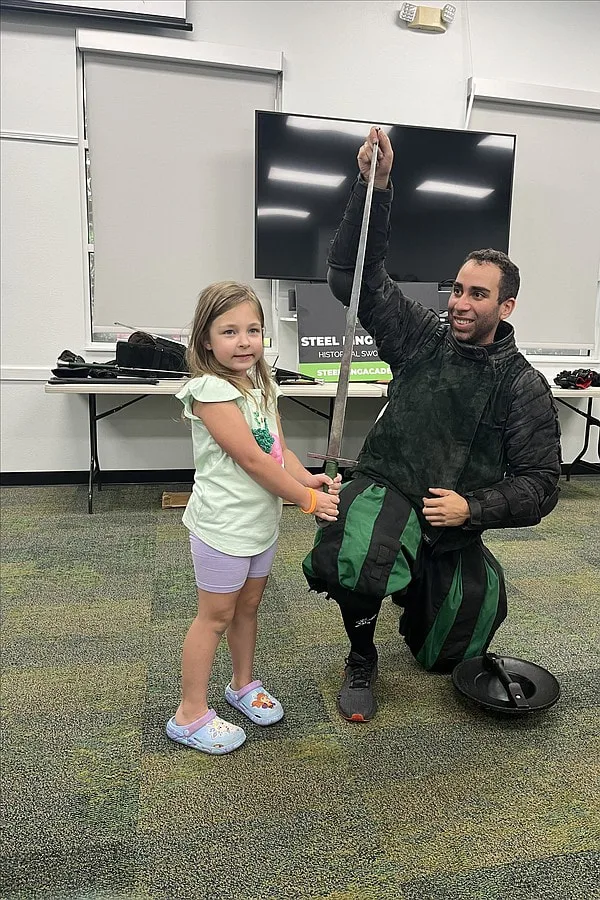 Instructor Chris at a summer reading program demonstration taking a photo with a child at the Braden River Library.
