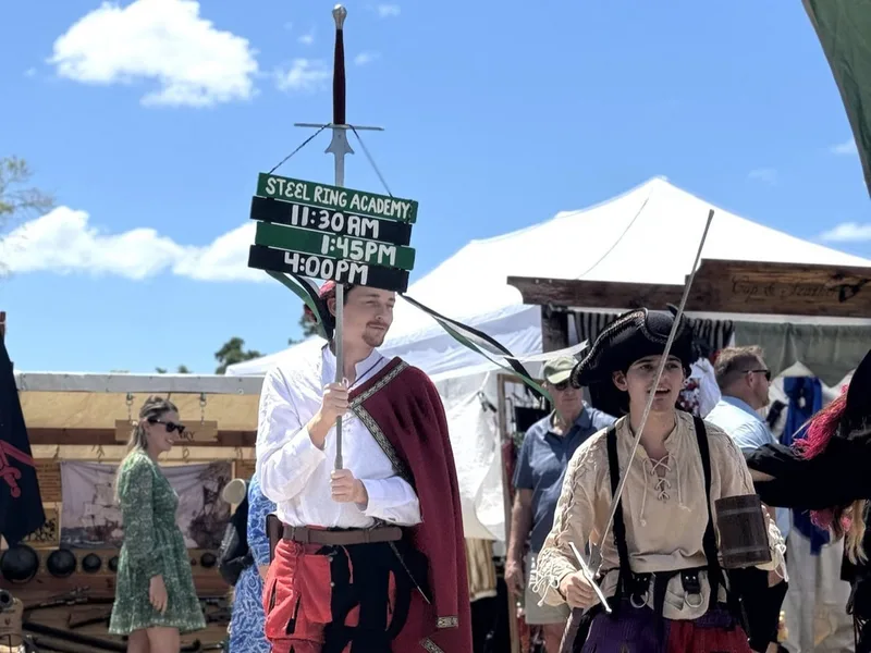 Students Dylan and Galloway promote Demonstration times at the St Petersburg Renaissance Faire